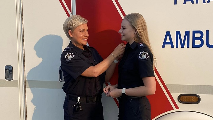 Stacy Elliott and her daughter Ashley Fell in paramedic uniforms standing in front of an ambulance