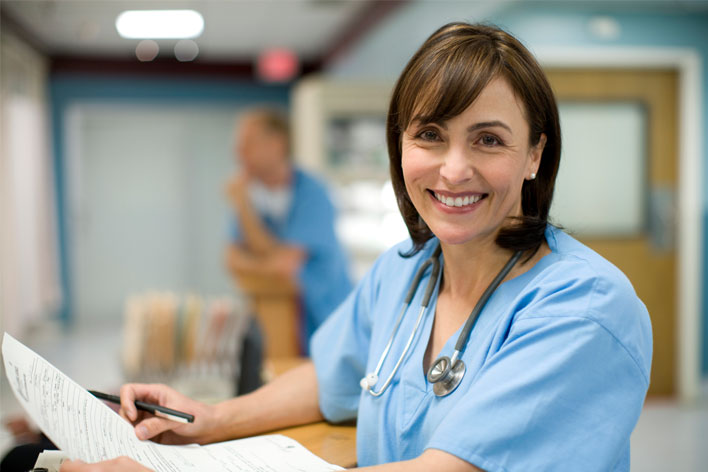 Nurse smiling at camera while filing out paper work